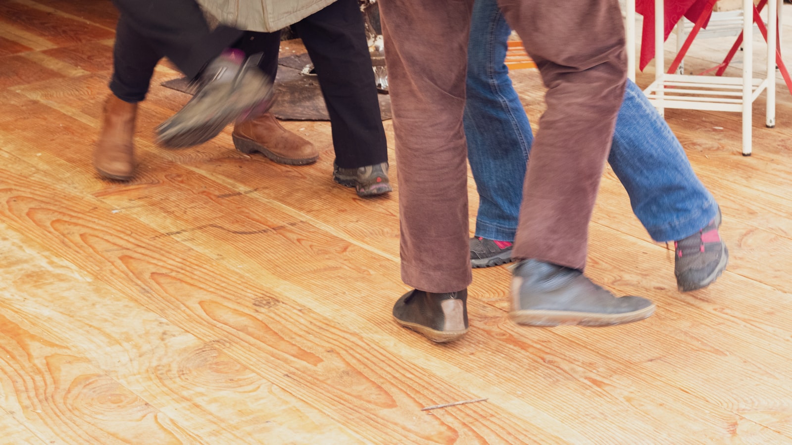 Four people dancing together on a wooden floor