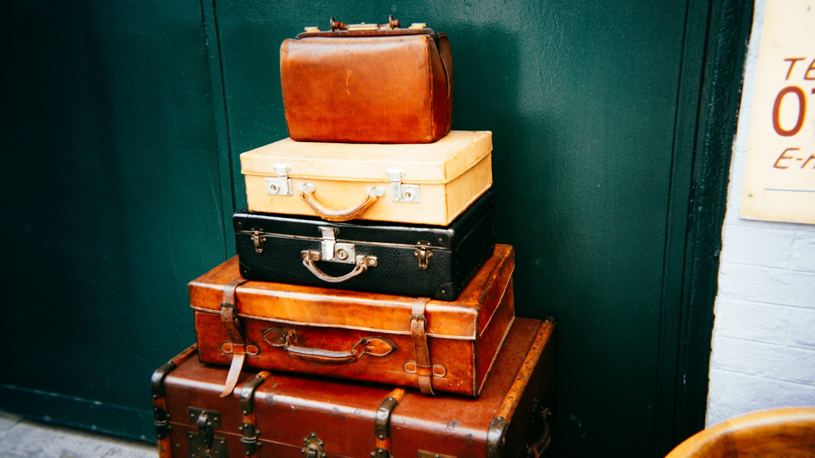 Stack of vintage suitcases against a dark green wall