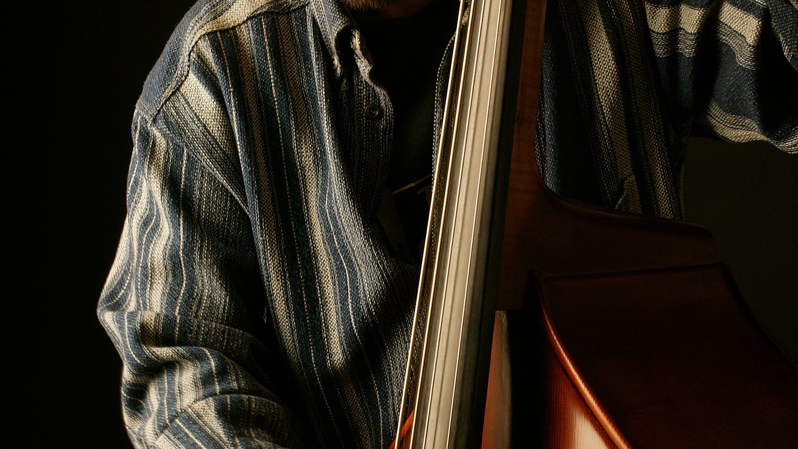 Musicien jouant de la contrebasse acoustique dans un studio sombre